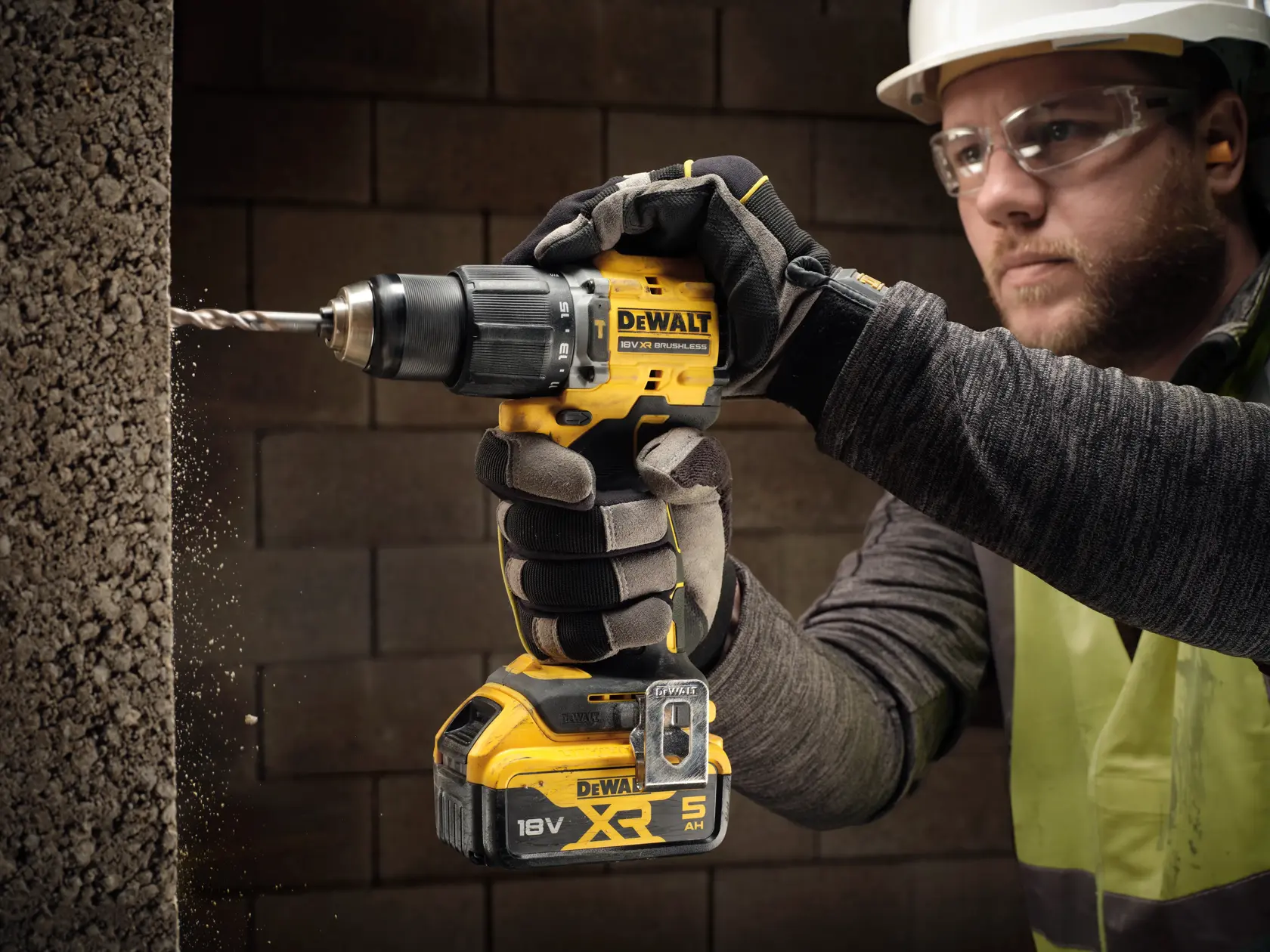 Taladro inalámbrico DEWALT perforando concreto, trabajador con guantes y equipo de seguridad.