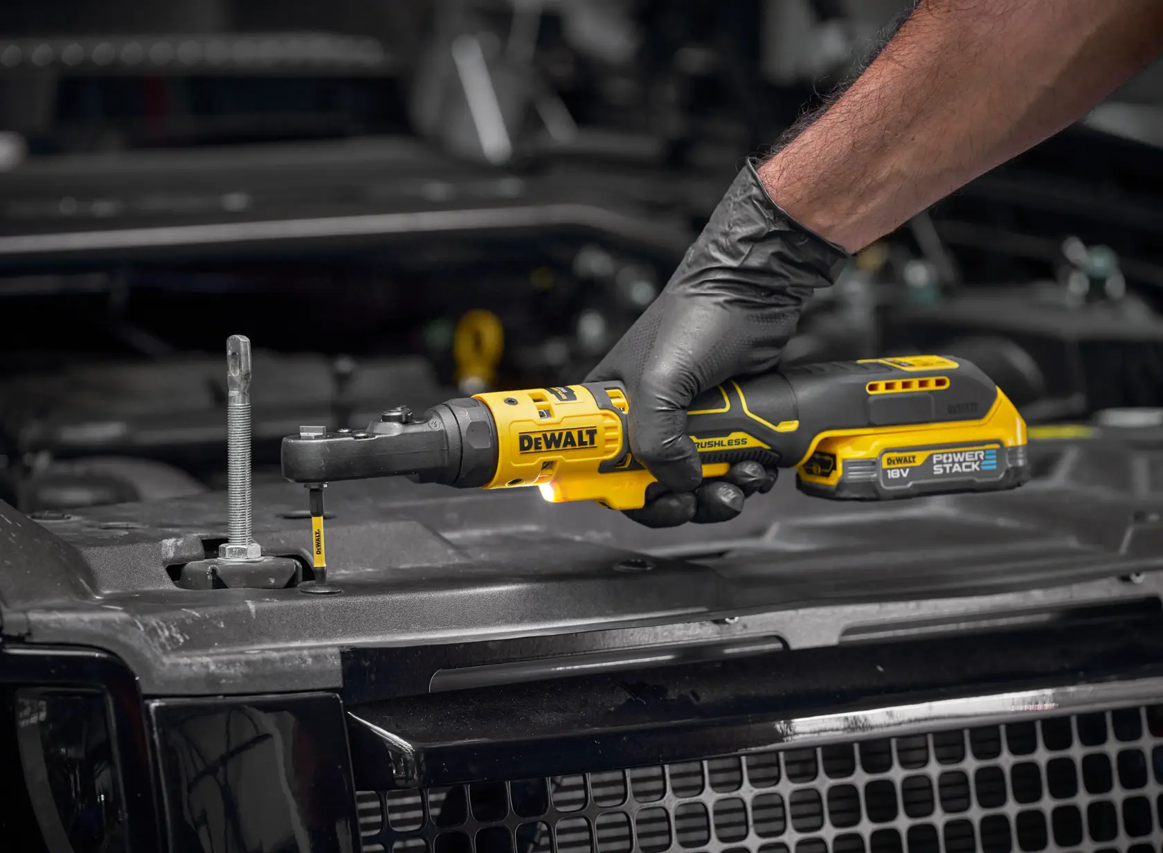 Clé à cliquet DEWALT SKUs DCF520N-XJ, DCF520N. Photographie. Main gantée, moteur auto.