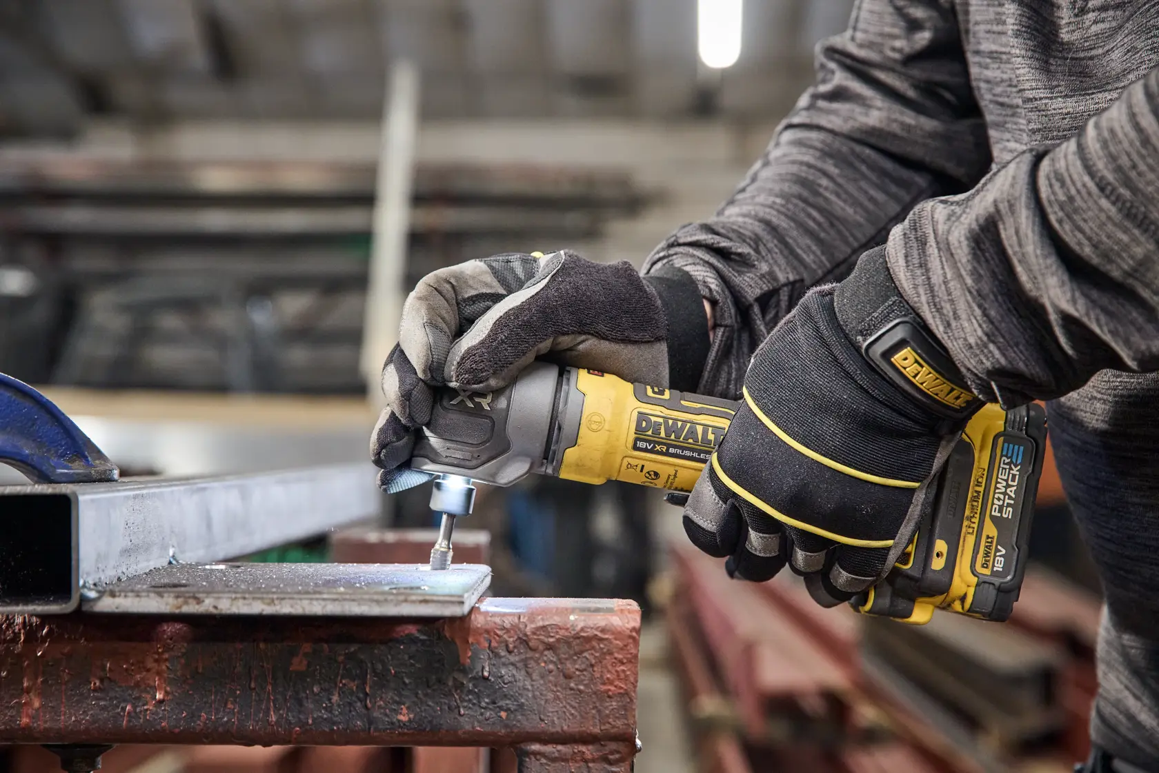 Outil DEWALT DCG421N-XJ, DCG421N utilisé par des mains gantées sur métal, atelier. Catégorie: photographie.