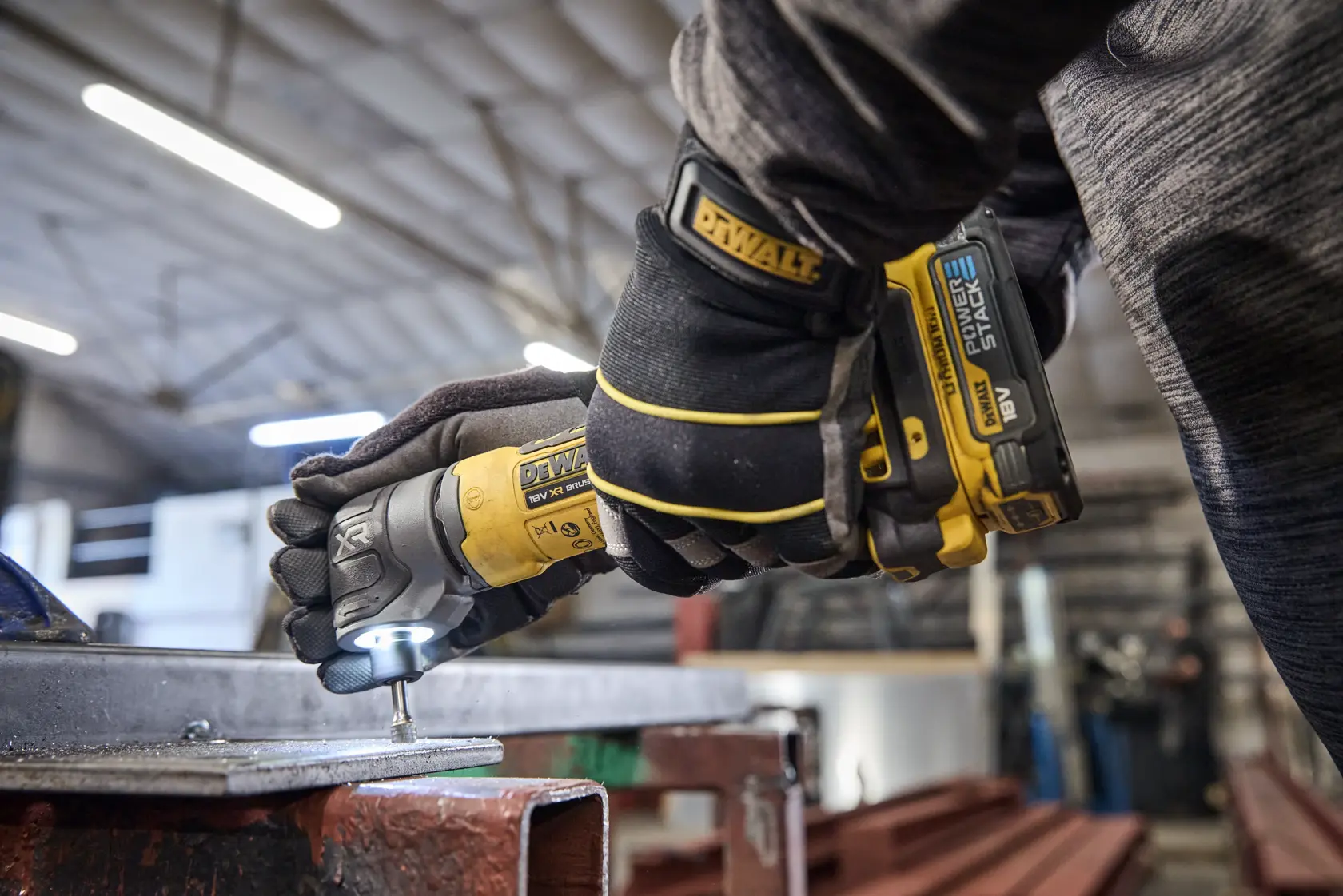 DEWALT DCG421N-XJ, DCG421N meule utilisée sur métal, atelier, opérateur avec gants.