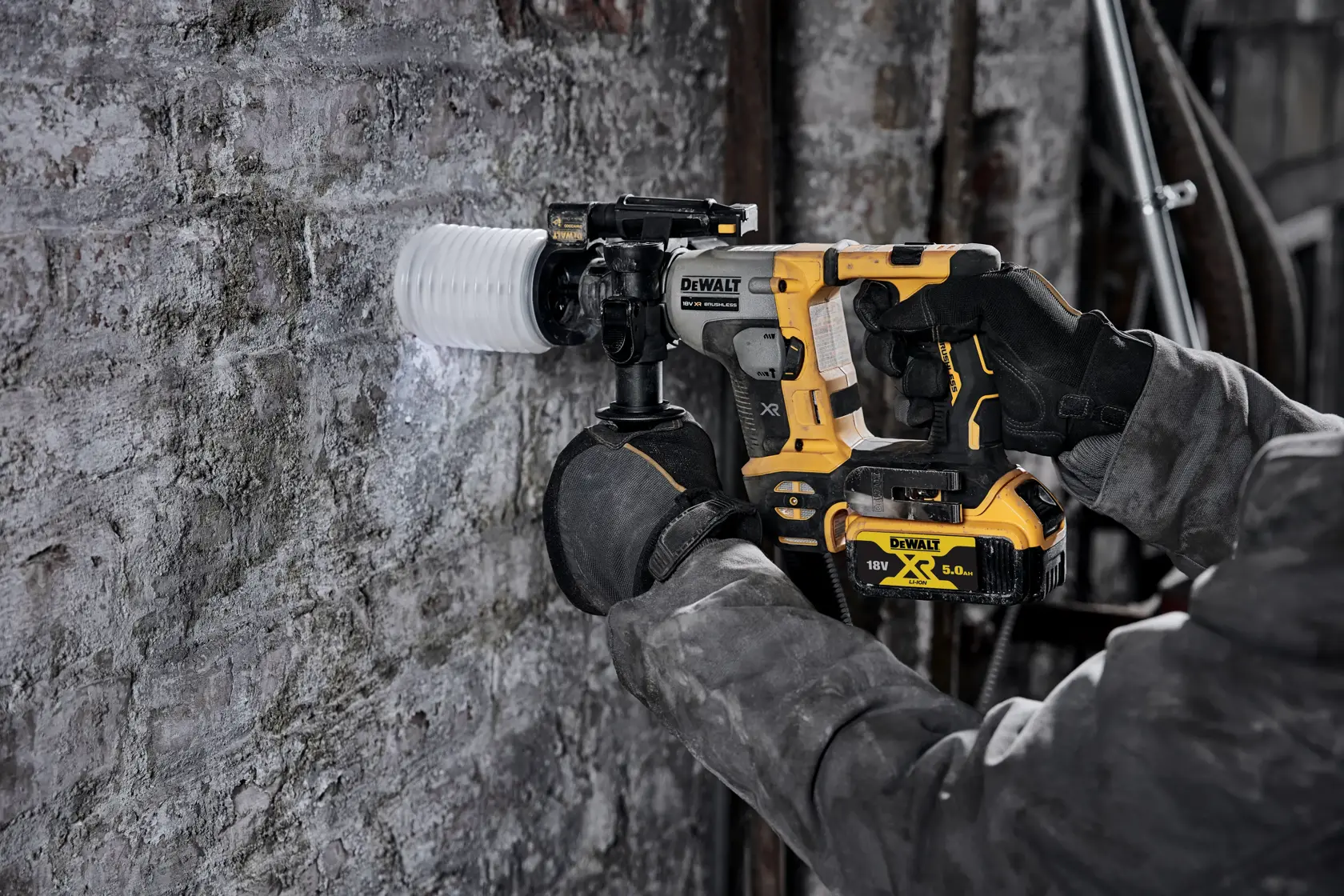Personne utilisant une perceuse rotative DEWALT sans fil sur un mur en béton, chantier.