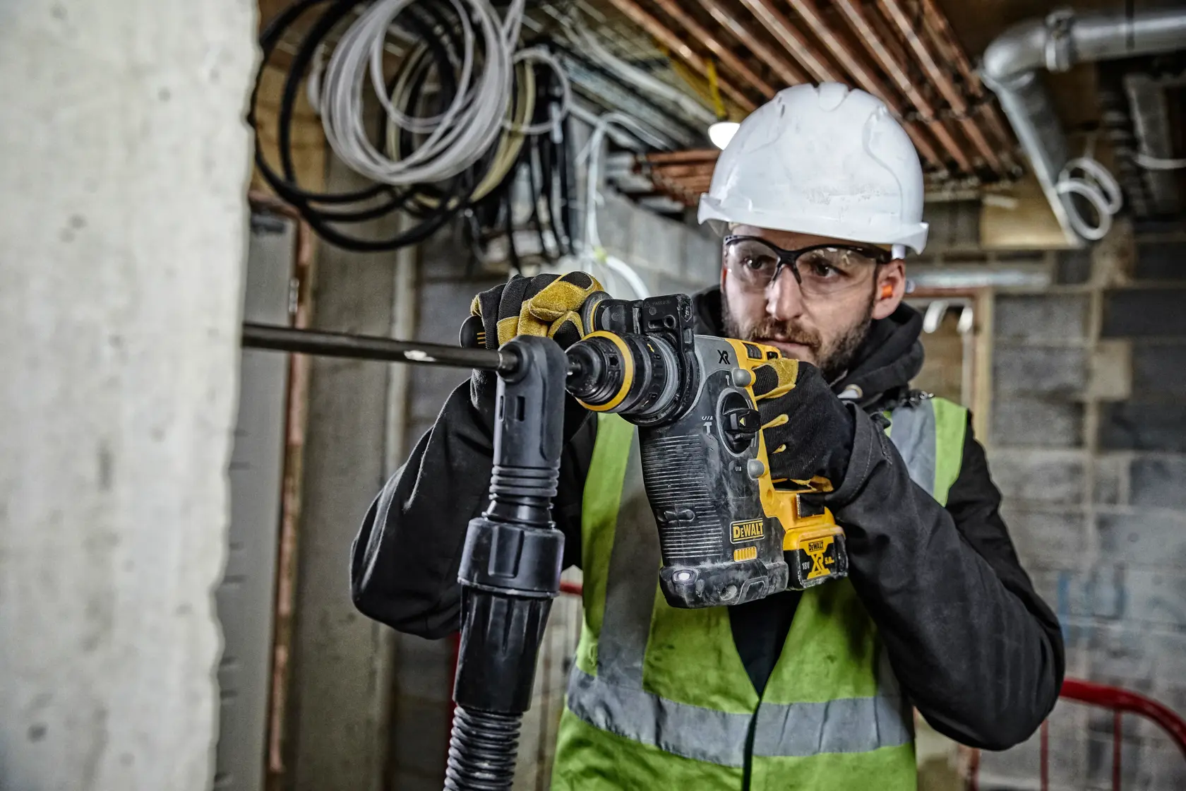 Arbeiter mit DEWALT DCH274P2T Schlagbohrmaschine auf einer Baustelle.