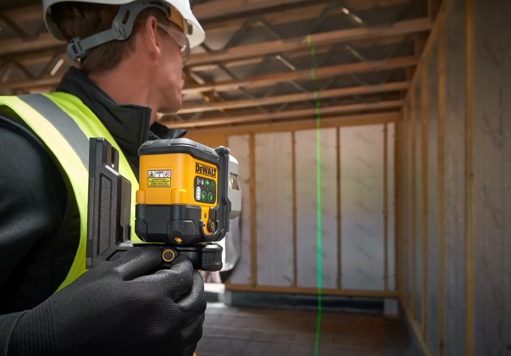 DEWALT-Laser-Nivelliergerät auf Stativ mit grüner Linie in Raum mit Möbelmontage.