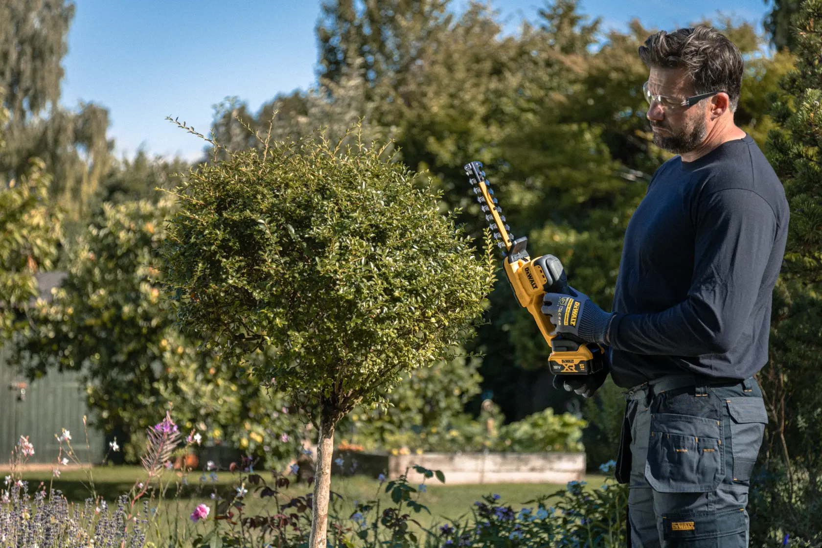 Personne avec taille-haie DEWALT DCMHT520N-XJ, DCMHT520D1-QW, DCMHT520D1, DCMHT520N à l’extérieur.