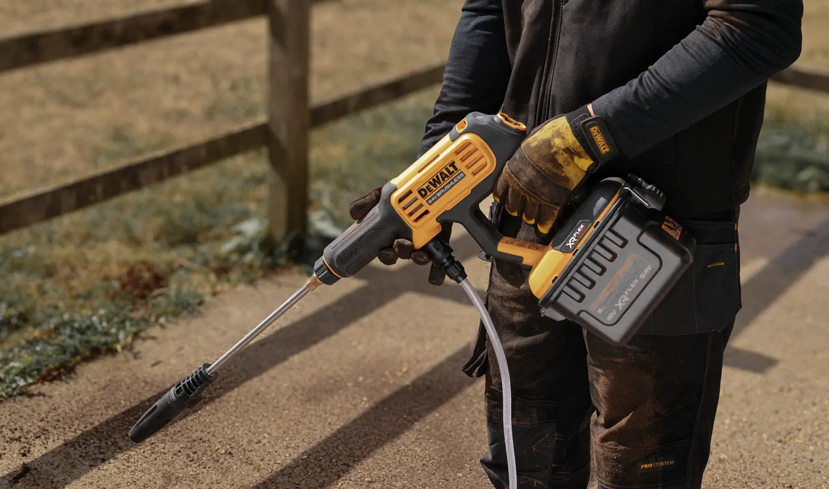 DEWALT DCMPW1000N, DCMPW1000N-XJ nettoyeur haute pression sans fil tenu dehors par une personne.
