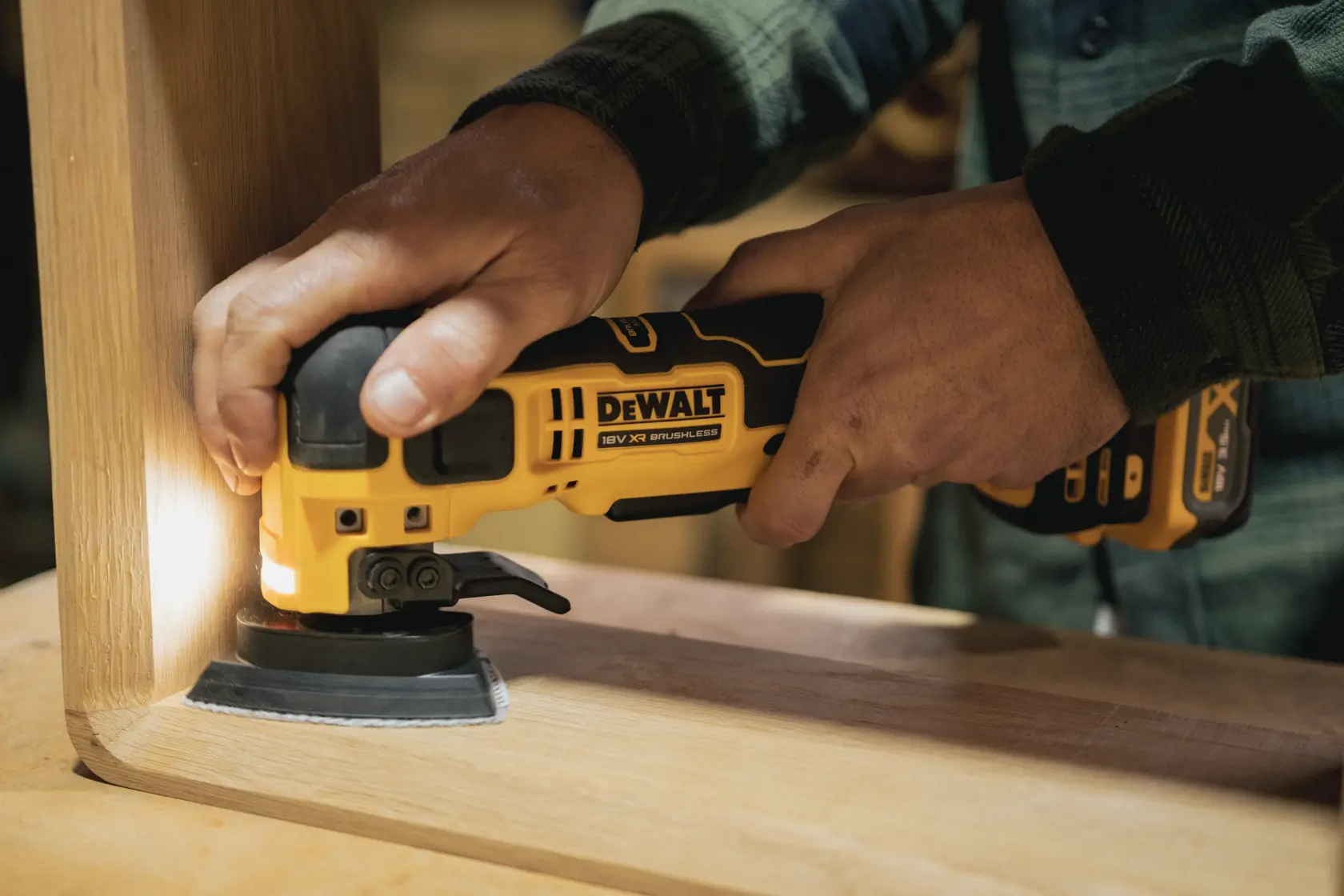 Person schleift eine Holzmöbelecke mit einem kabellosen DEWALT Multifunktionswerkzeug.