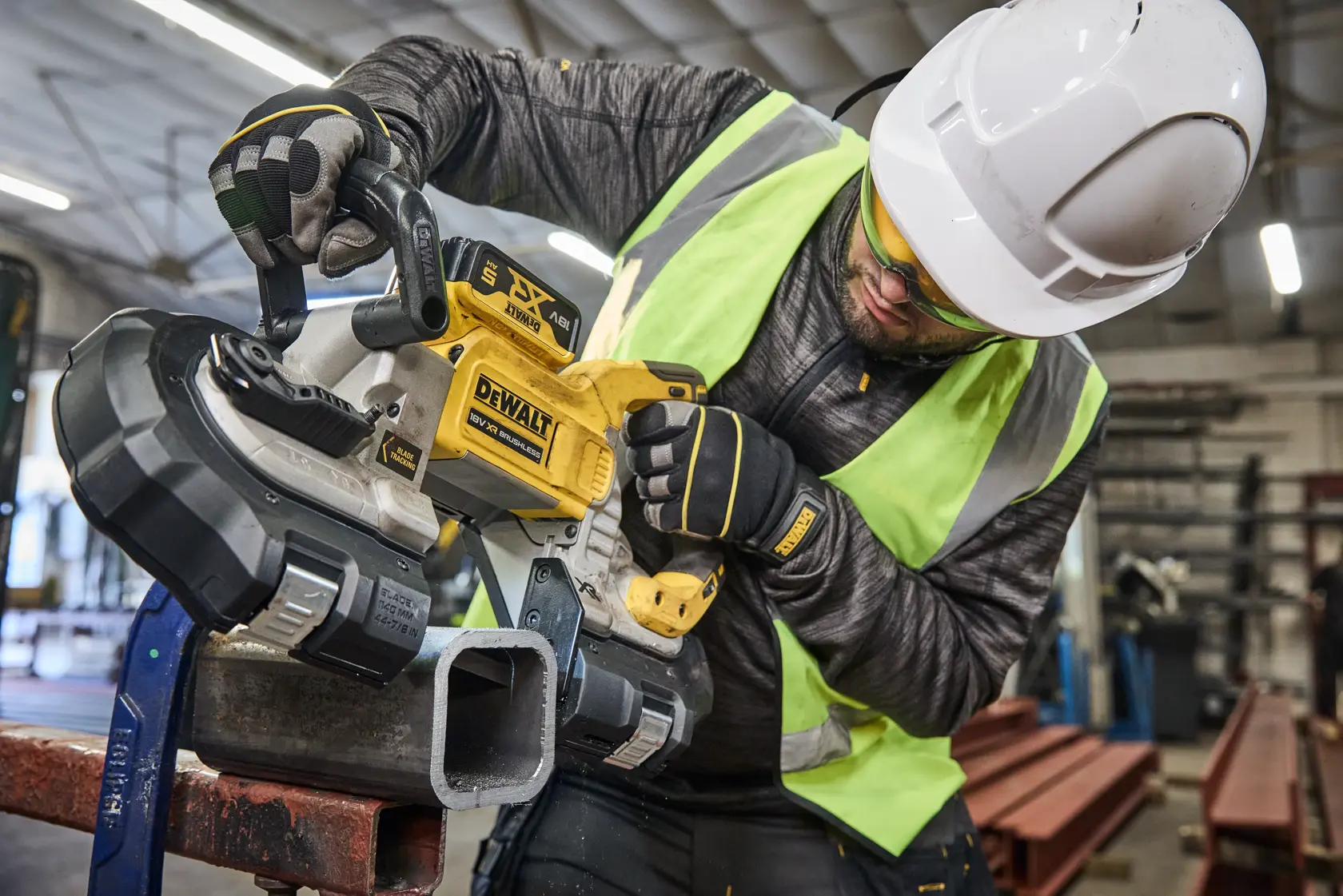 Ouvrier avec DEWALT DCS374N, DCS374N-XJ scie sur tube métal, équipé de protection.