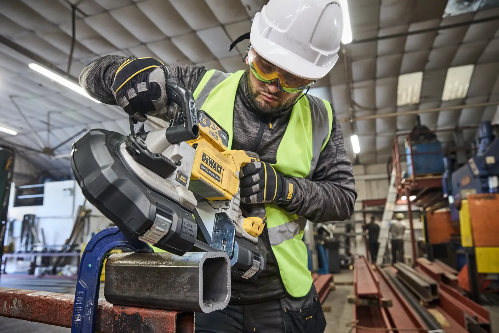 Ouvrier utilisant DEWALT scie à ruban, DCS374N, DCS374N-XJ, pour couper du métal en atelier.