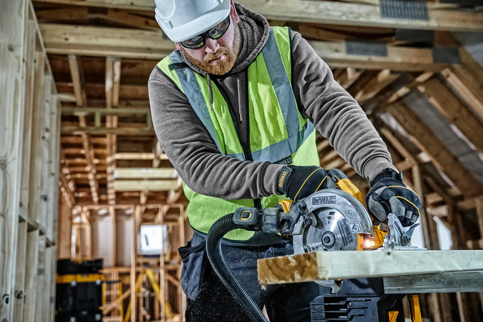 Ouvrier coupe du bois avec scie circulaire DEWALT DCS570 sur chantier. Équipement de sécurité et gants portés.