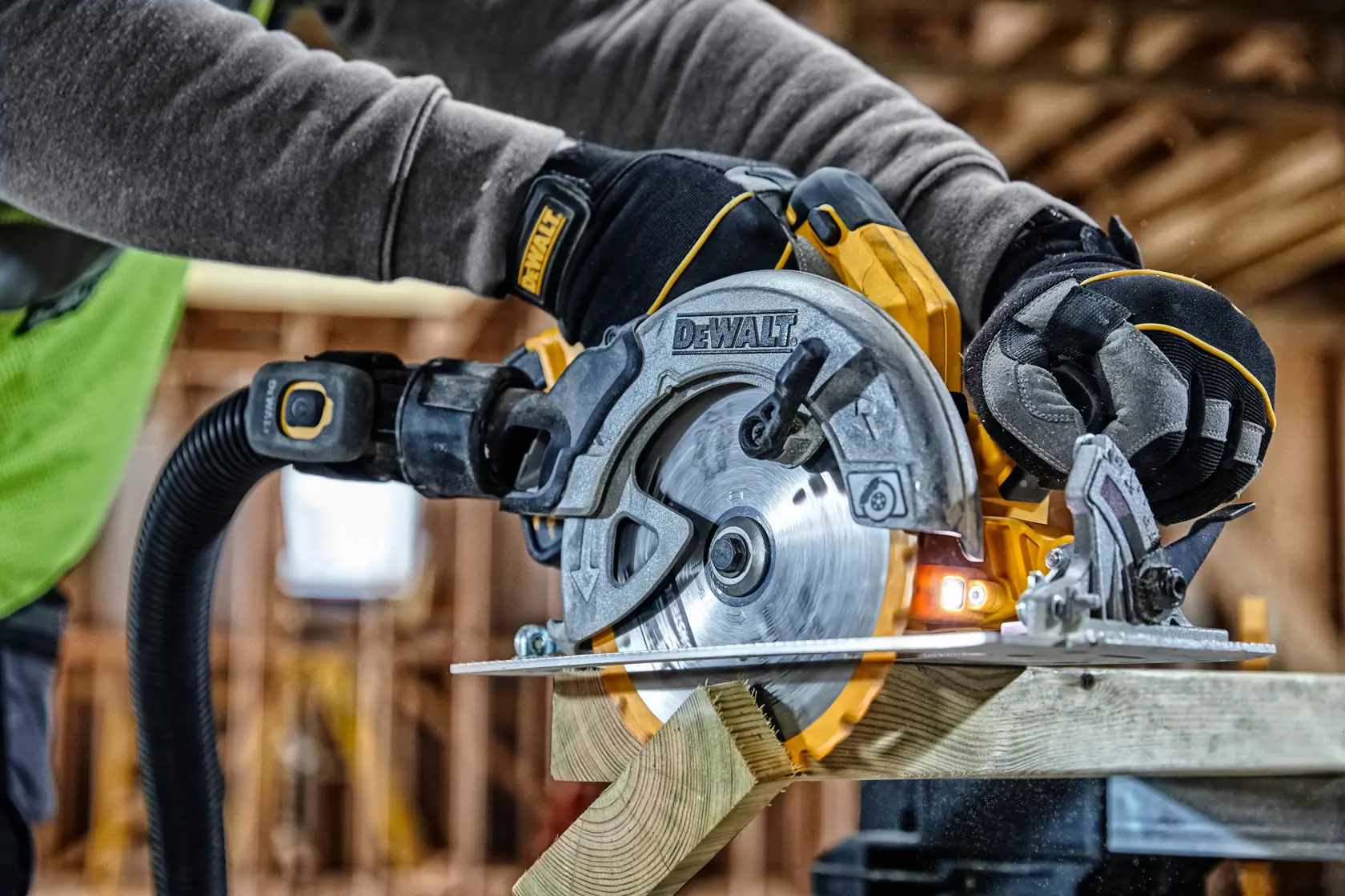 Scie circulaire DEWALT coupant du bois, manipulée par un ouvrier ganté sur un chantier.