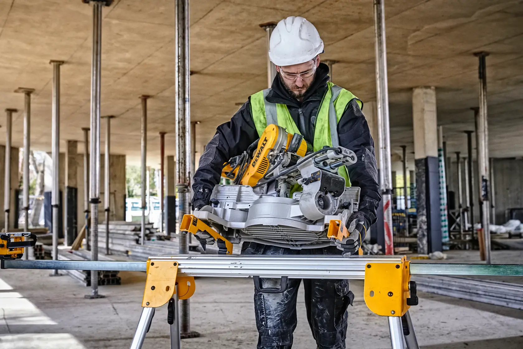 Support de scie DEWALT DE7033 utilisé sur chantier, un travailleur équipé d’un casque et gilet de sécurité.