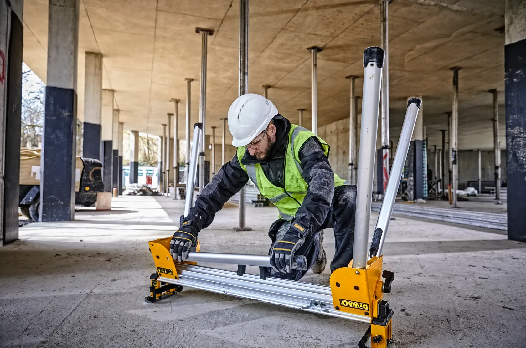 Ouvrier assemblant un support DEWALT DE7033 sur un chantier avec des piliers en béton.