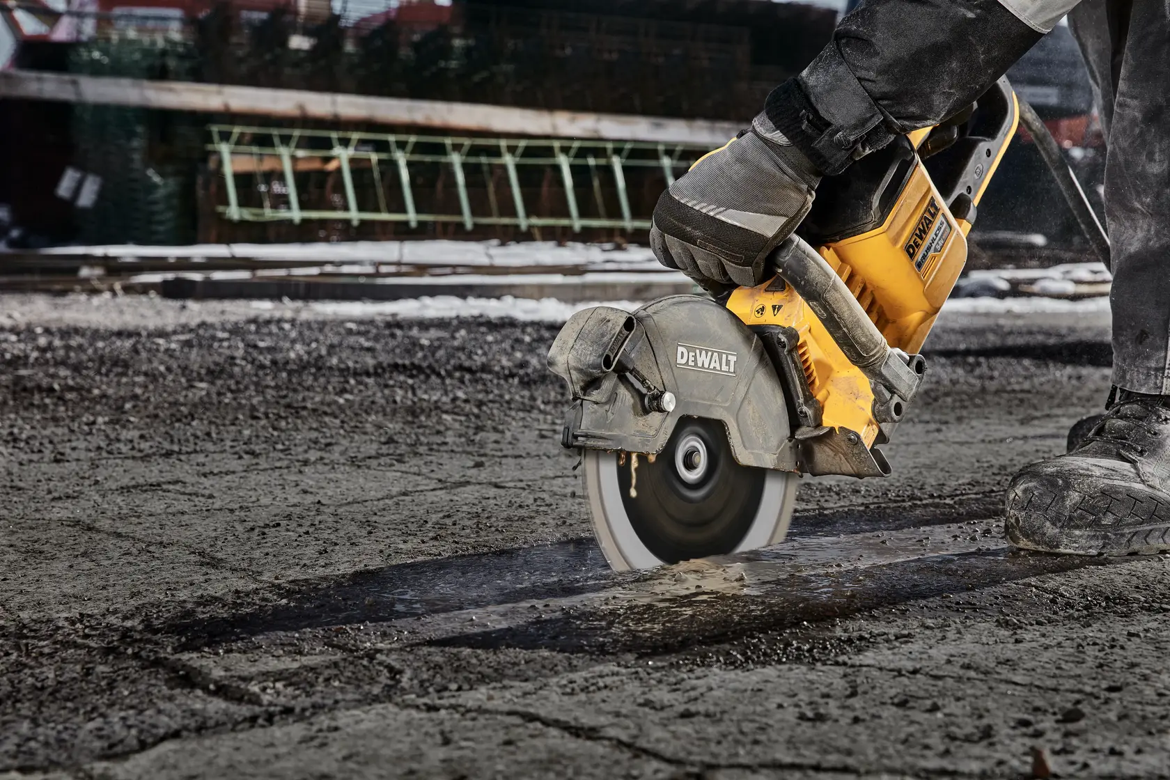 Photo scie DEWALT coupant asphalte; SKU DT20466-QZ, DT20466. Ouvrier avec gants utilisant l’outil.