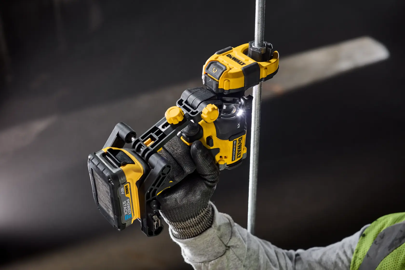 Una herramienta DEWALT es sostenida por una mano con guante, cortando una varilla metálica.
