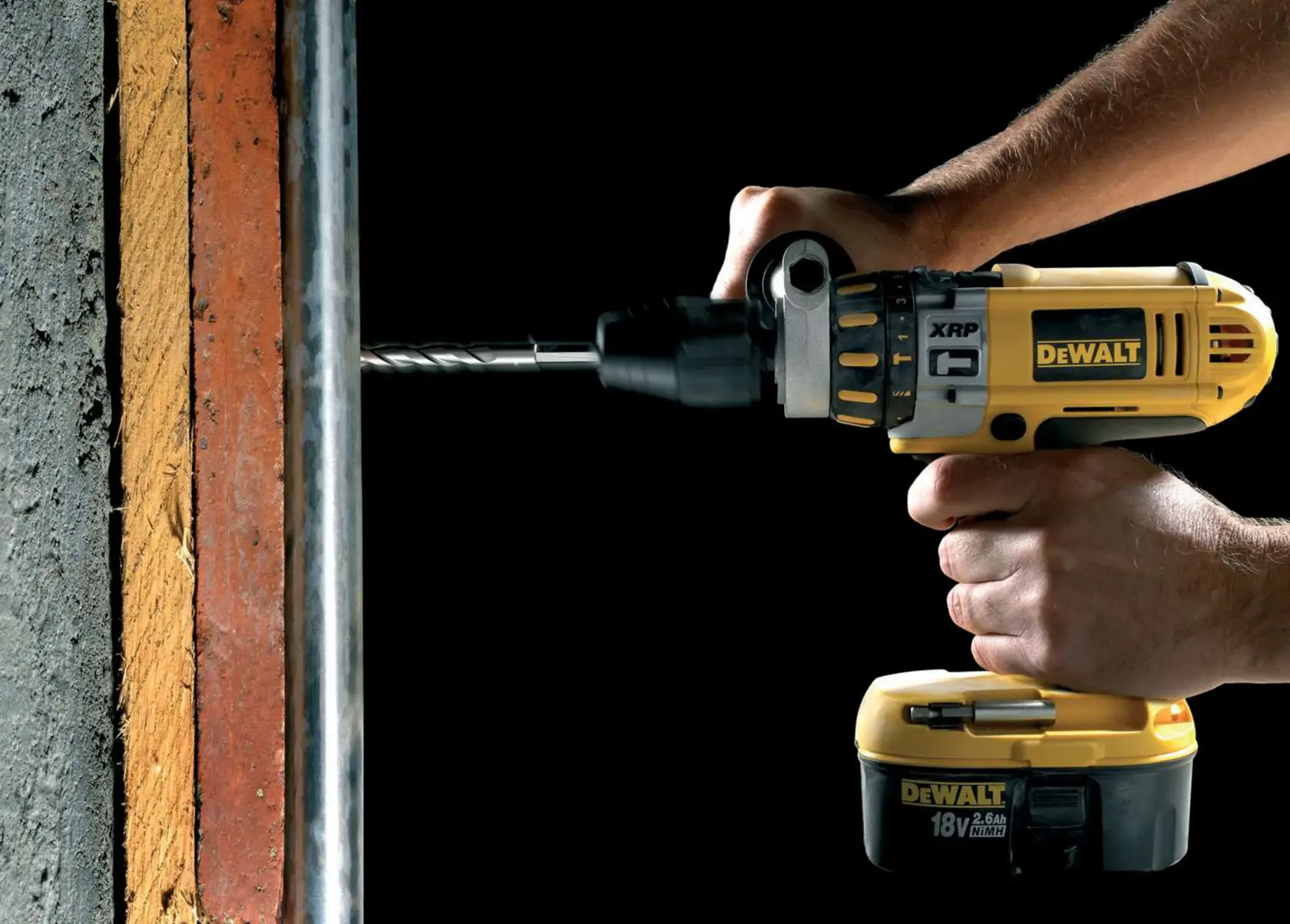 Perceuse DEWALT en action, perçant un mur en béton. Des mains tiennent l’outil jaune contre la surface.
