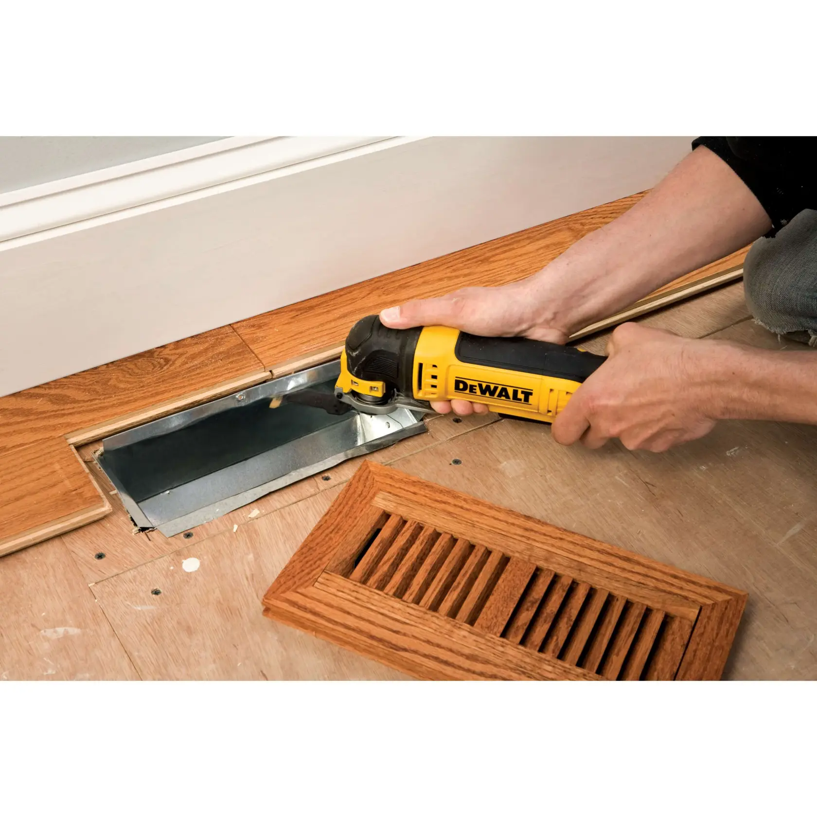 Une personne découpe du parquet près d'une grille d'aération avec un outil DEWALT.