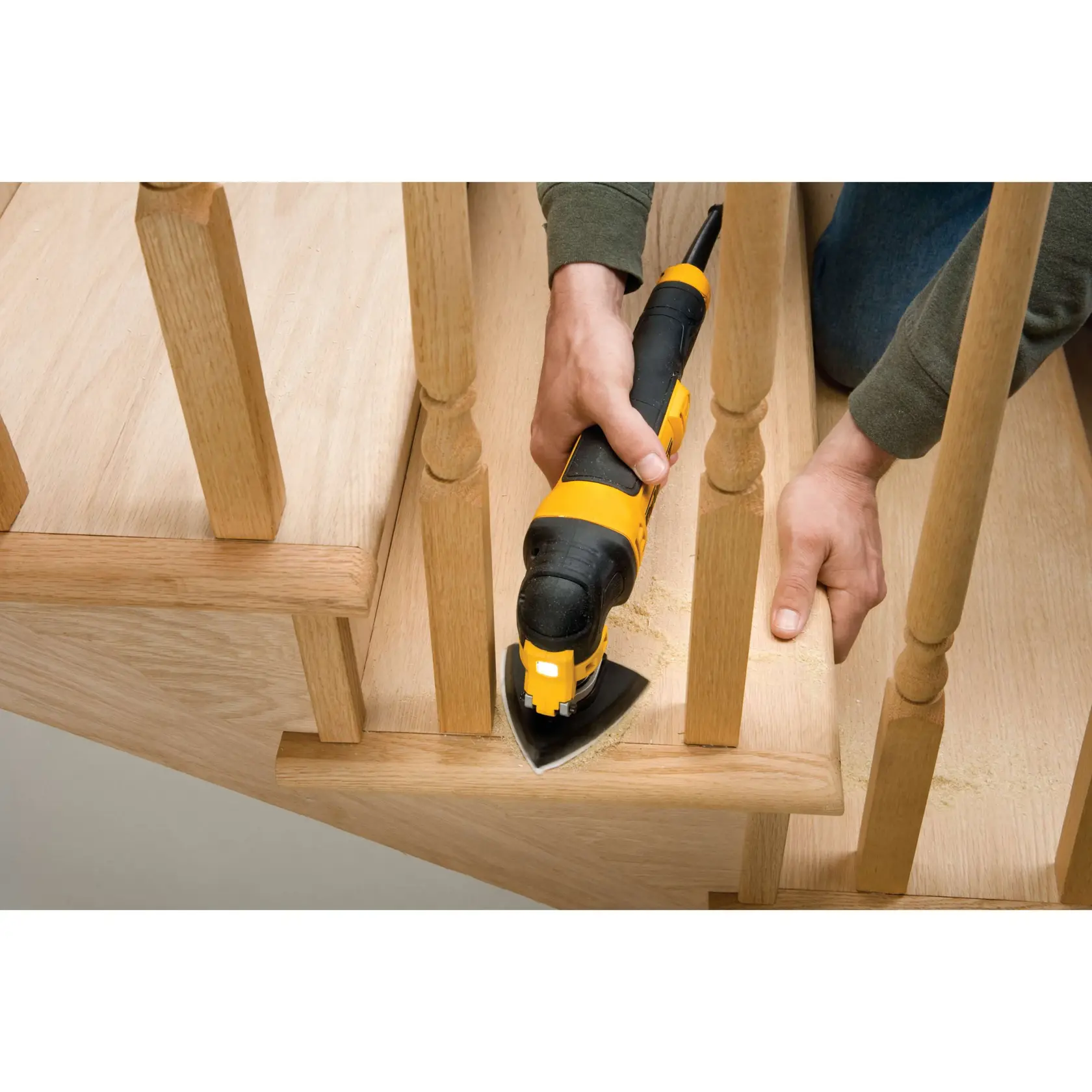 Personne ponçant des escaliers en bois avec un outil DEWALT entre les balustres.