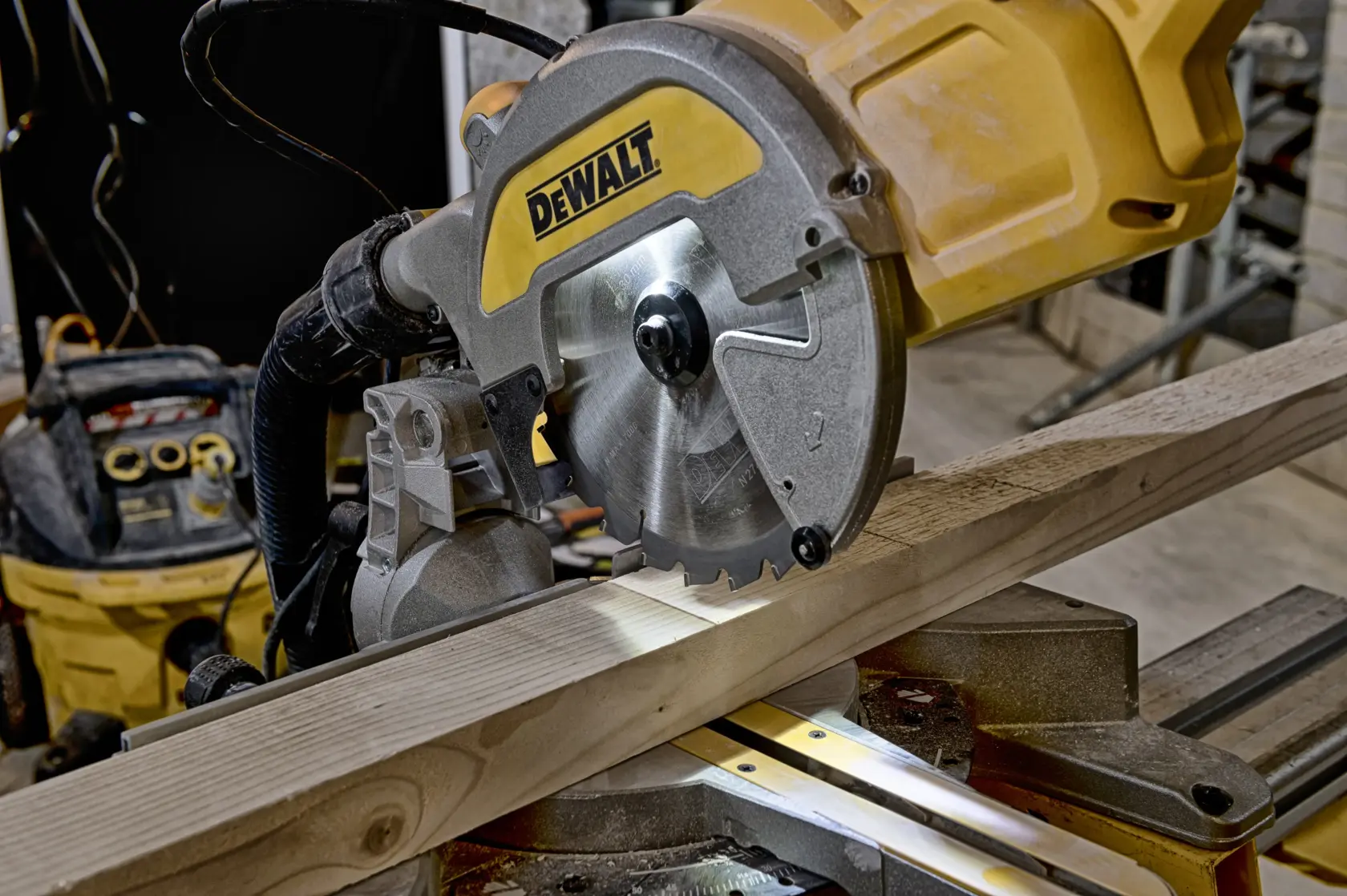 Scie à onglet DEWALT coupant une planche de bois dans un atelier.
